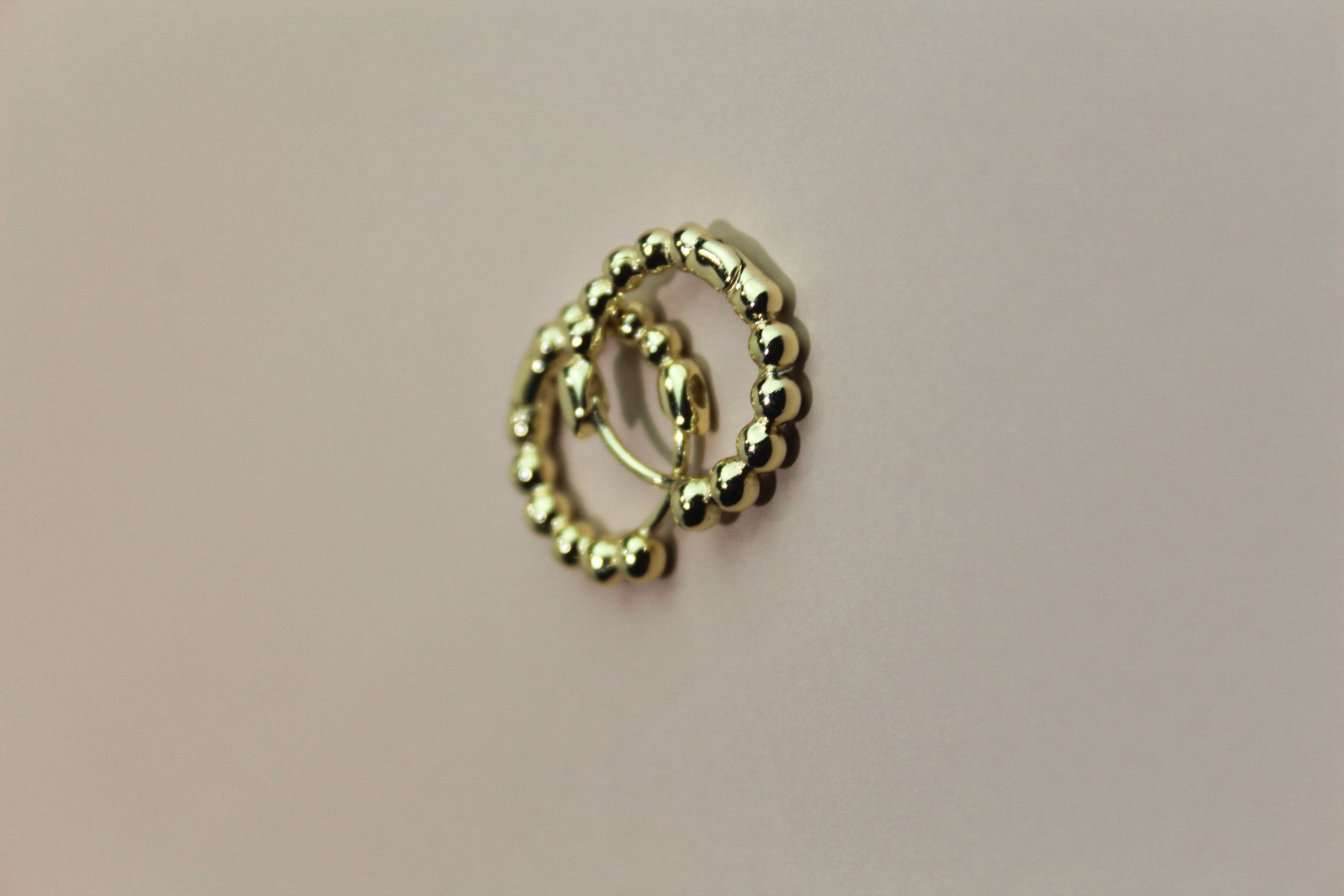 Gold hoop earrings on a beige background